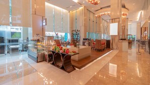 Un moderno vestíbulo de hotel con una isla central, zona de estar y mostrador de recepción.