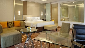 Una habitación de hotel moderna con cama, sofá, sillón y una mesa de vidrio.