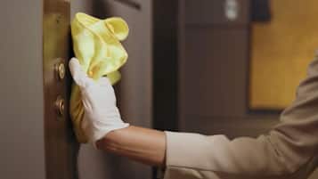 A person cleaning a door handle with a yellow cloth.