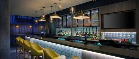 A bar area with multiple stools, a bar counter, and a variety of bottles and glasses.