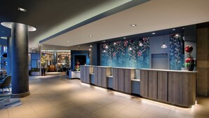 A modern hotel lobby with a reception desk, seating area, and a large wall mural. - Leonardo Hotel Swindon  (Swindon)