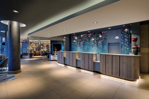 A modern hotel lobby with a reception desk, seating area, and a large wall mural. - Leonardo Hotel Swindon  (Swindon)