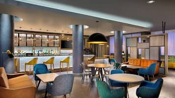 Een moderne bar met een toog, zitplaatsen, verschillende stoelen en tafels.
