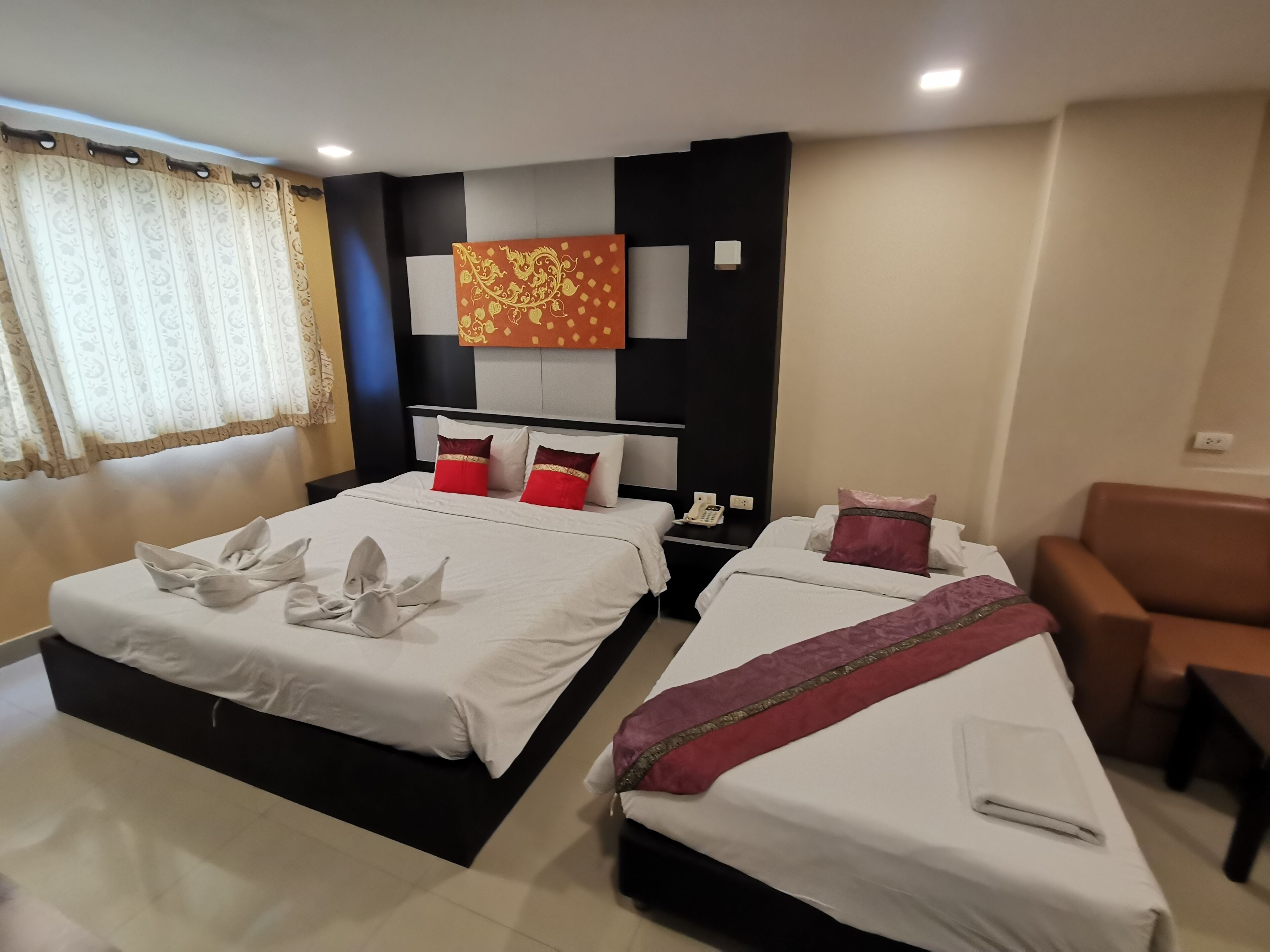 A hotel room with two beds, a sofa, a telephone, and a decorative wall piece.