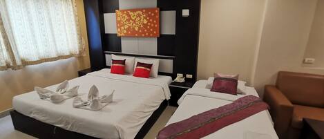 A hotel room with two beds, a sofa, a telephone, and a decorative wall piece.