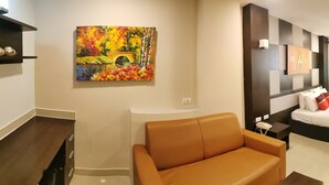 Une chambre d’hôtel avec un lit, un canapé, une télévision et des œuvres d’art accrochées aux murs.