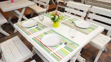 A dining table set with white plates, cutlery, and a glass of water, with a green and orange striped table runner.