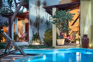 A pool area with lounge chairs, a hammock, and a staircase leading to an upper level. - Pousada Surfing Jeri (Jijoca de Jericoacoara)