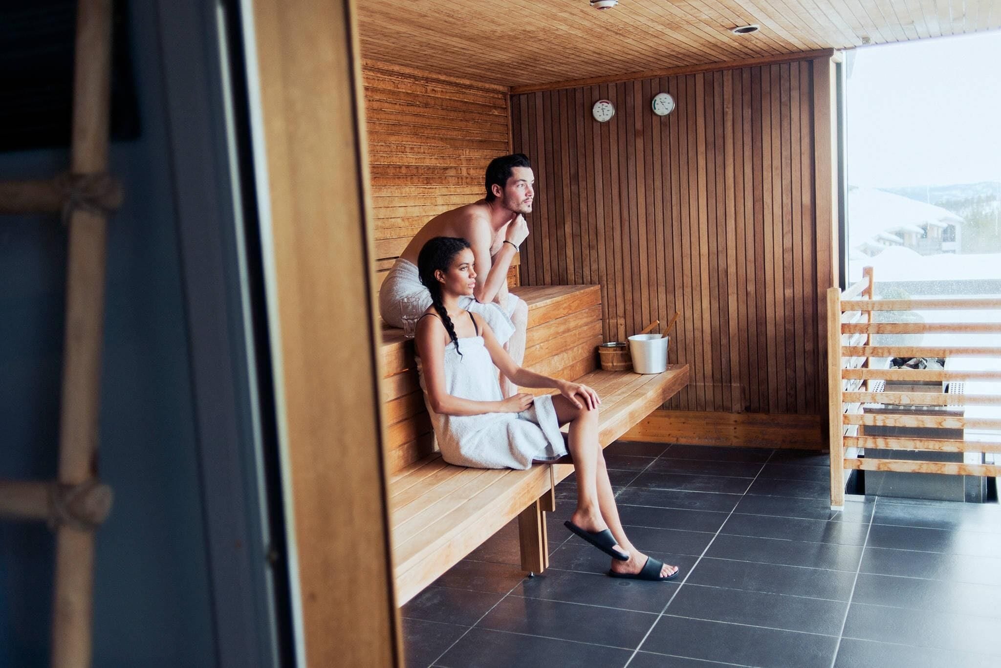 A sauna with wooden benches, a tiled floor, and a view of the outside.