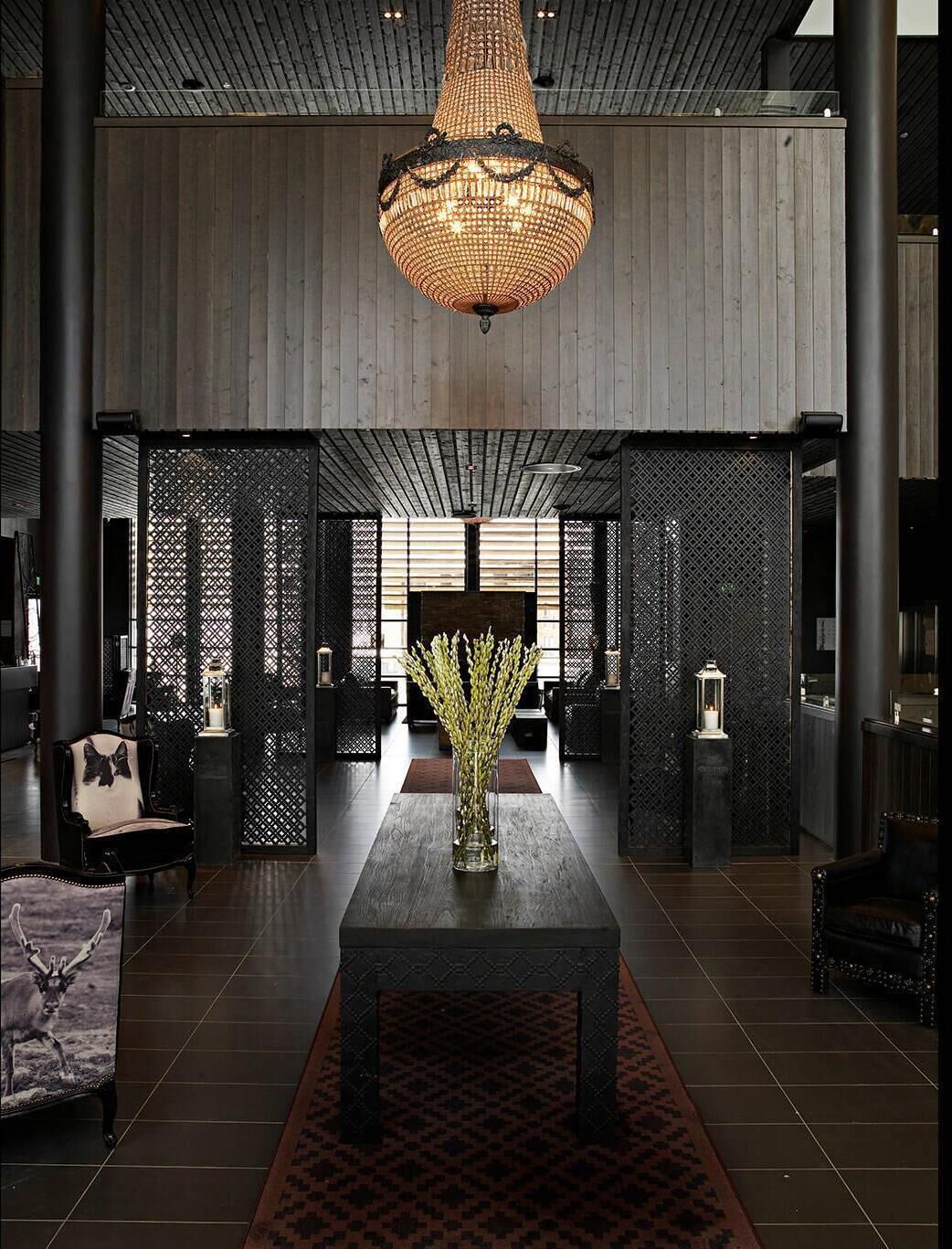 Un hall d’entrée avec une table centrale, des vases décoratifs et un grand lustre.