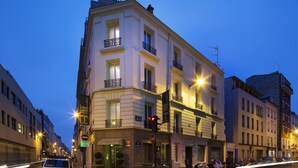 A multi-story building with balconies, a sign indicating a restaurant, and a traffic light. - Le Fabe Hotel (Paris)