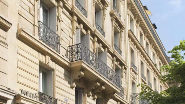 A multi-story building with a classic architectural style, featuring ornate balconies and large windows. - Le Fabe Hotel (Paris)