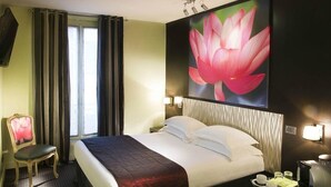 A hotel room with a large bed, a chair, a desk, and a wall-mounted TV. - Le Fabe Hotel (Paris)