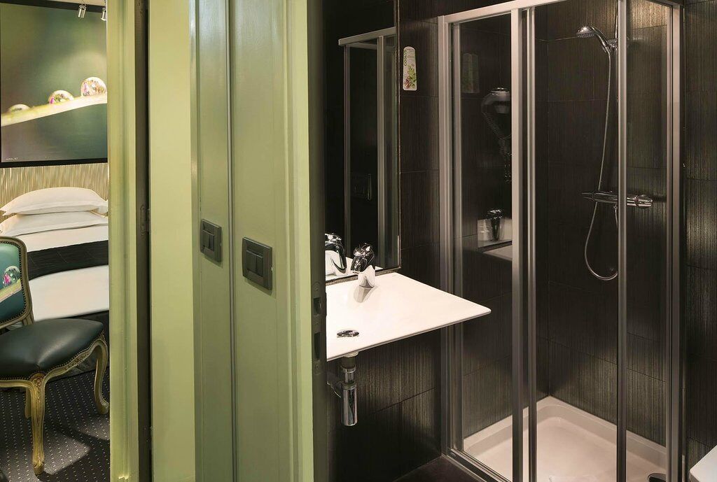 Een badkamer met een wit wastafelmeubel, een douchecabine van glas en een spiegel.