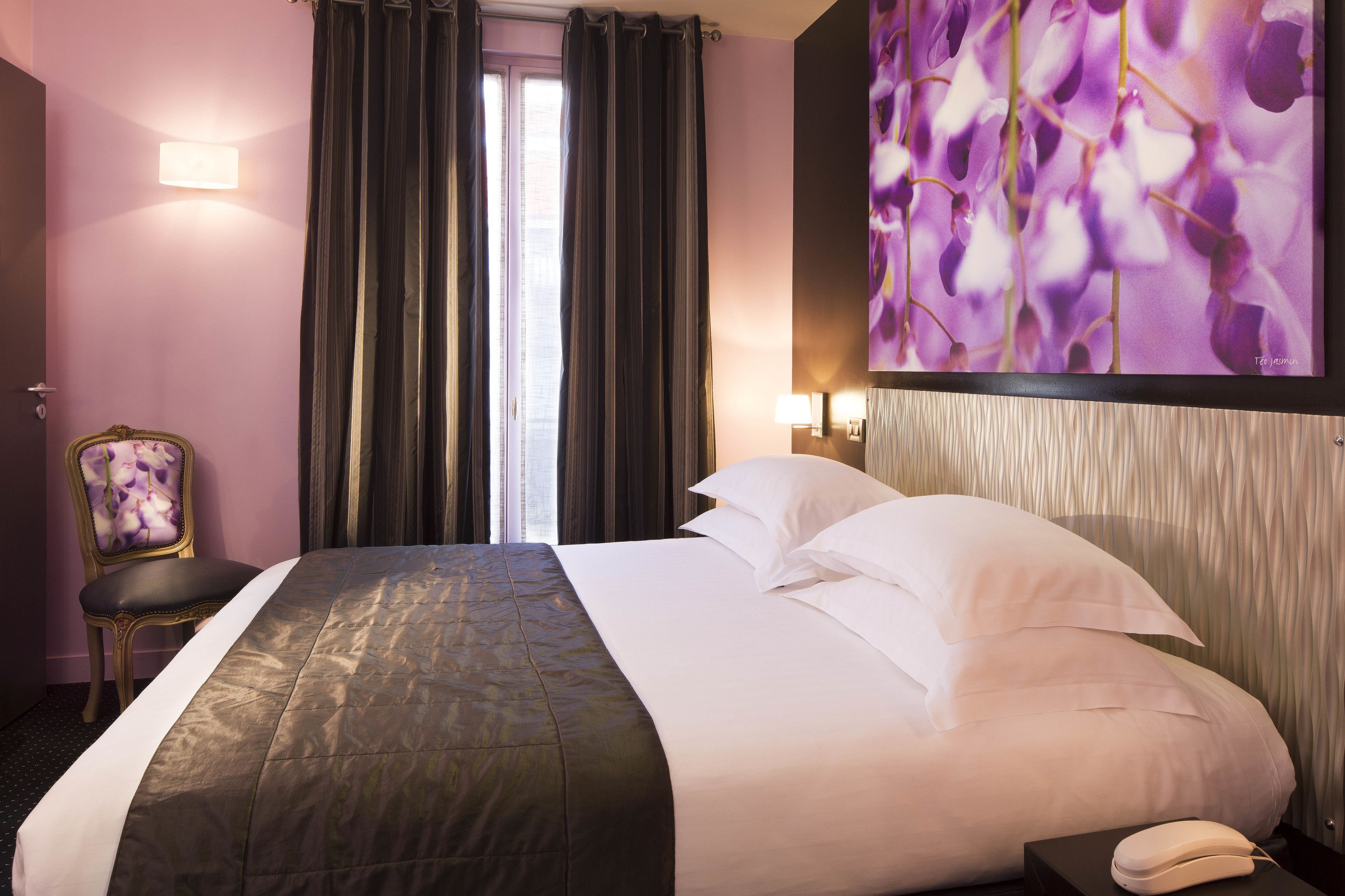 Habitación de hotel con una cama grande, una silla, un escritorio y un teléfono en la pared.