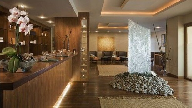 Un moderno vestíbulo de hotel con un mostrador de recepción de madera, un área de descanso con sillas y una decoración con rocas.