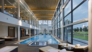 Una piscina interior moderna con zonas de descanso y grandes ventanales que ofrecen vistas del paisaje circundante.