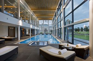 Una piscina interior moderna con zonas de descanso y grandes ventanales que ofrecen vistas del paisaje circundante.