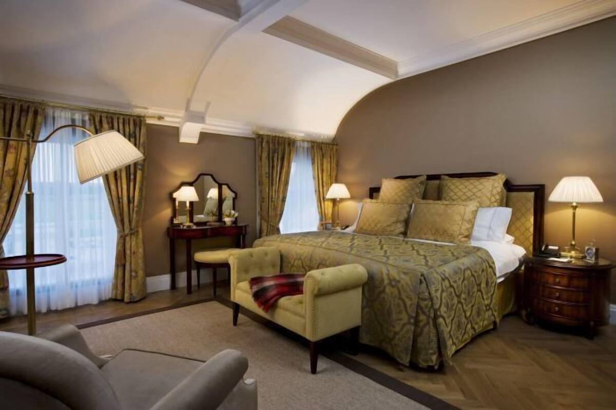 A hotel room with a large bed, two bedside tables, a chair, and a lamp.