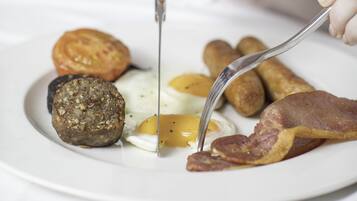 Ein Frühstücksteller mit Eiern, Würstchen und Speck.