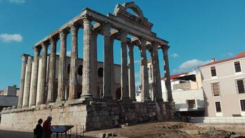 Ruinas antiguas con columnas, una base de piedra y una estructura parcialmente conservada.