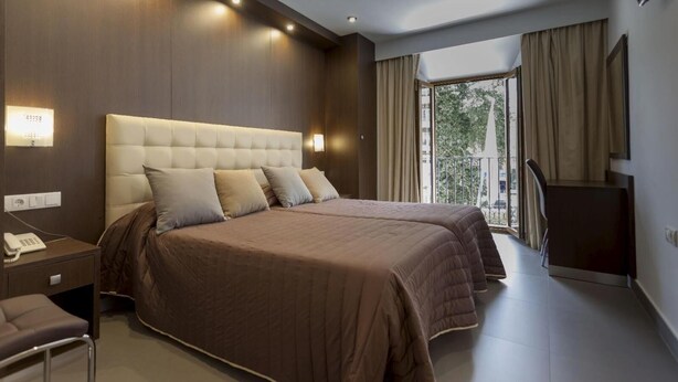 A modern hotel room with a large bed, bedside tables, a desk, and a TV. - Hotel Rambla Emérita (Merida)
