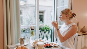 Una mesa de desayuno con croissants, café y un tazón de frutos rojos.