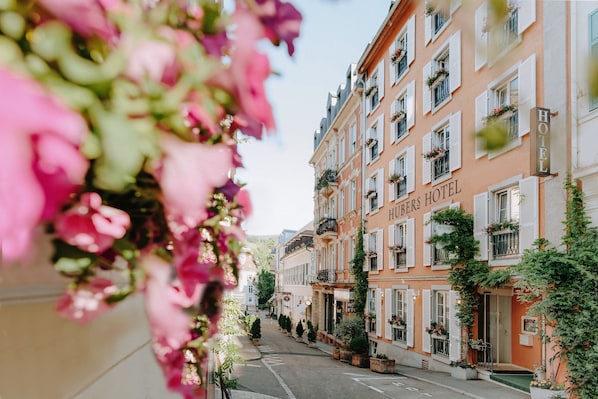 Experience the charm of HUBERTS HOTEL, a classic European-style building with elegant balconies and a warm, inviting atmosphere.