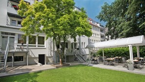 A courtyard with a lawn, outdoor seating area, and a covered section. - Baltic Hotel (Lübeck)