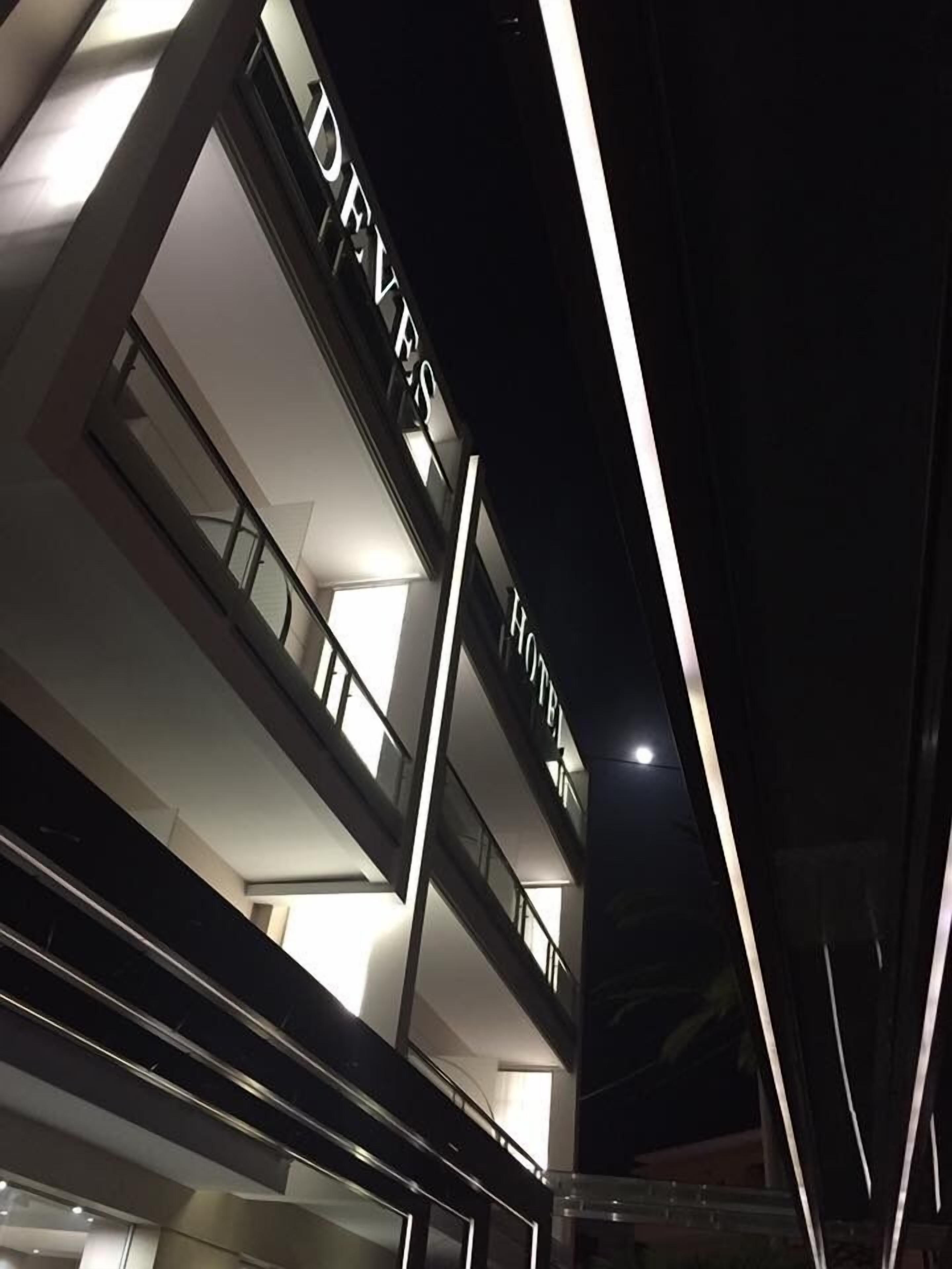 Un hotel moderno con un llamativo letrero que dice 'DEVES HOTEL' en la fachada.