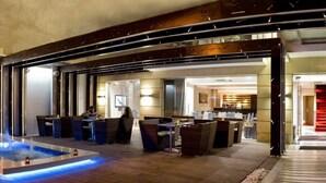 Eine moderne Hotellobby mit einem zentralen Wasserspiel, einer Sitzecke und einer Treppe zu den oberen Etagen.