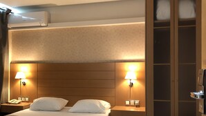 Ein Hotelzimmer mit einem großen Bett, zwei Nachttischen mit Lampen, einem Kleiderschrank und einer Klimaanlage.