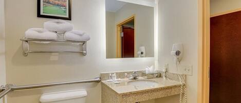 A bathroom with a toilet, a sink with a mirror, a towel rack, and a hairdryer.