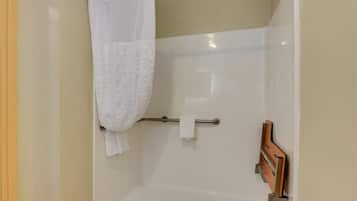 A shower area with a white shower curtain, a towel rack, and a wooden panel.