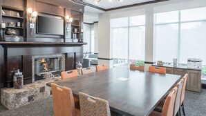 A conference room with a large table, chairs, a fireplace, and a television on the wall. - Hilton Garden Inn Dothan (Dothan)