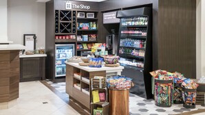 A coffee shop with a counter, shelves stocked with snacks, a refrigerated display, and a beverage dispenser. - Hilton Garden Inn Dothan (Dothan)