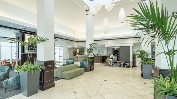 A spacious lobby with a high ceiling, large windows, and multiple seating areas. - Hilton Garden Inn Dothan (Dothan)