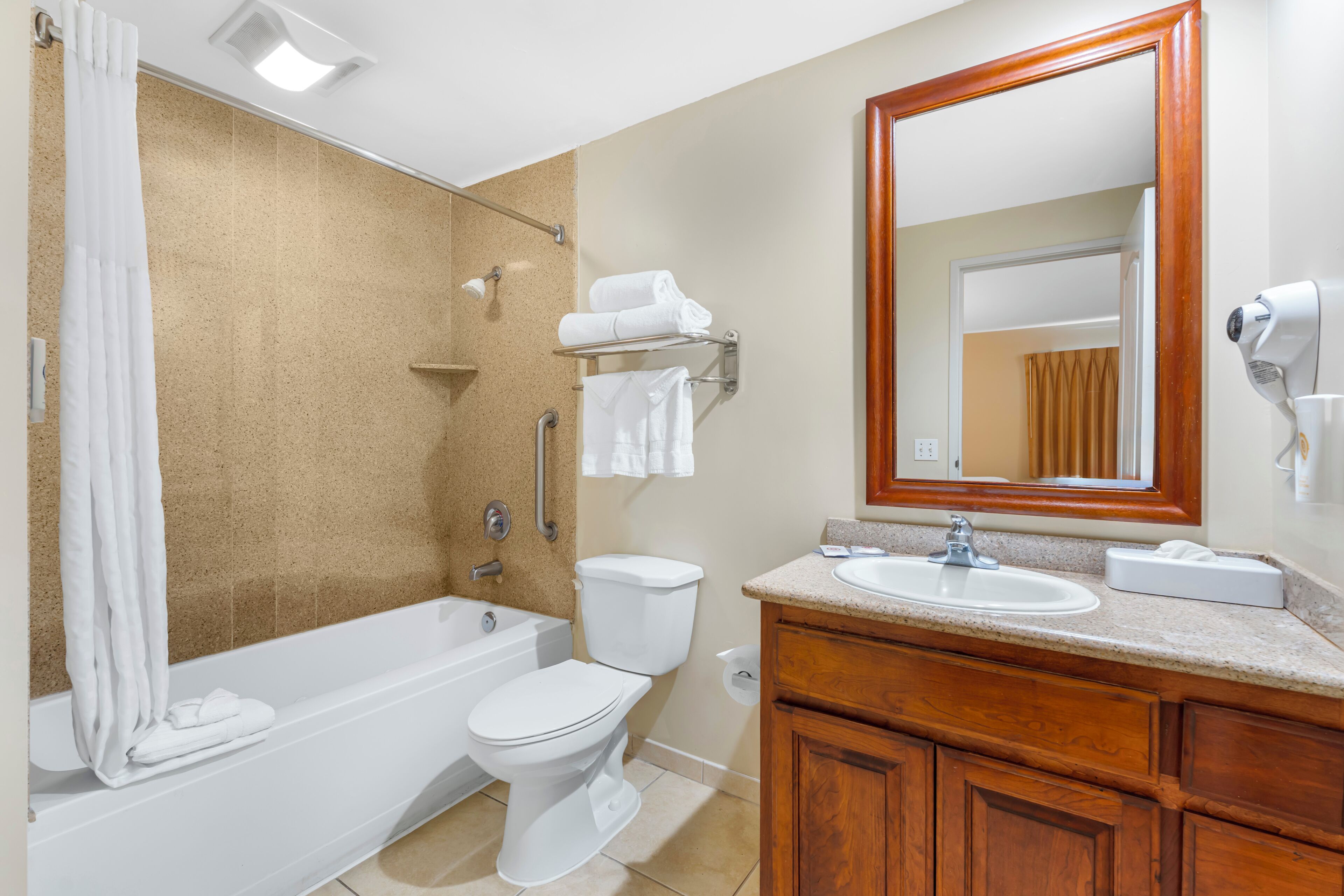 A bathroom with a bathtub, toilet, and vanity with a mirror.