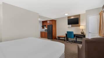 Ein Hotelzimmer mit Bett, Schreibtisch, Stuhl, Fernseher und einer Küchenzeile.