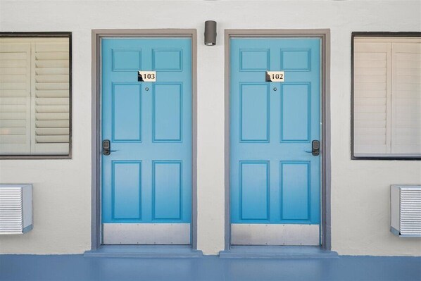 Two blue doors with numbers 103 and 102, flanked by windows with blinds. - Geary Parkway Motel At Mine Hospitality (San Francisco)