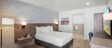 A modern hotel room with a large bed, bedside lamps, a desk, and a TV.