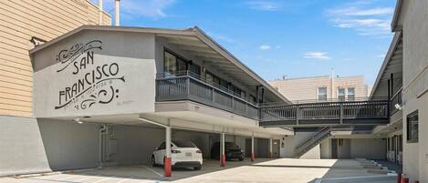 Un parking couvert, une voiture blanche et un bâtiment portant l’inscription « SAN FRANCISCO ».