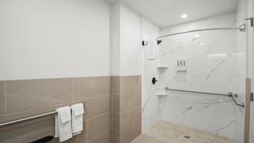 A modern bathroom with a shower, a towel rack, and a marble wall.