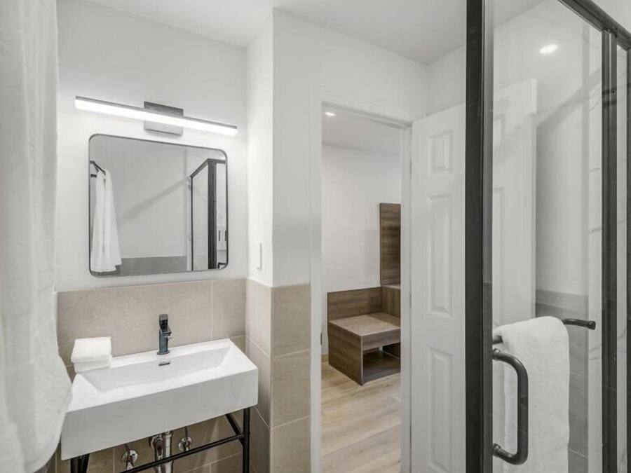 Een moderne badkamer met een wit wastafelmeubel, spiegel en handdoekhouder.