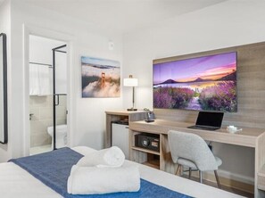 A hotel room with a bed, a desk with a laptop, a TV, and a shower area. - Geary Parkway Motel At Mine Hospitality (San Francisco)