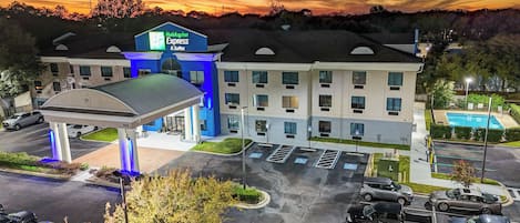 A Holiday Inn Express & Suites with a gas station, parking, and a pool.
