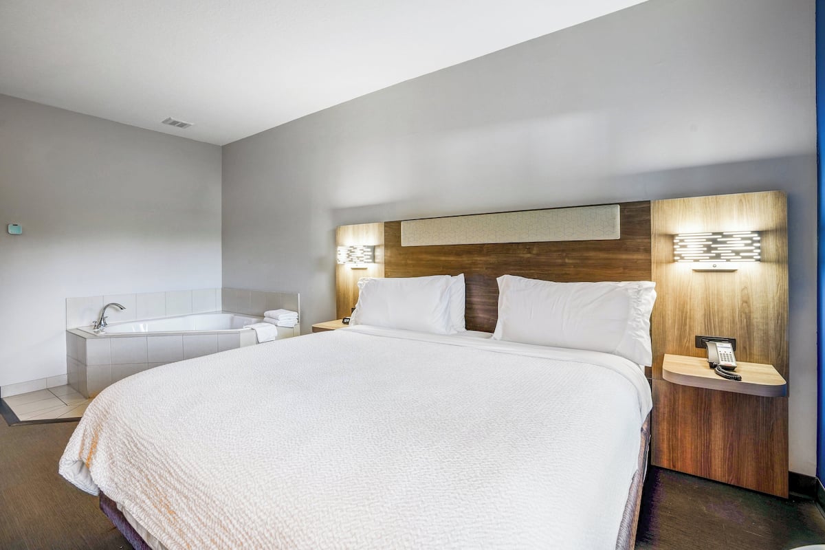 Een moderne hotelkamer met een groot bed, een inloopbad en bedlampjes.