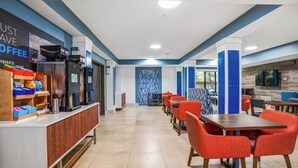 A modern hotel lobby with a long reception desk, red chairs, and a coffee bar. - Holiday Inn Express & Suites Jacksonville - Atlantic Beach by IHG (Atlantic Beach)
