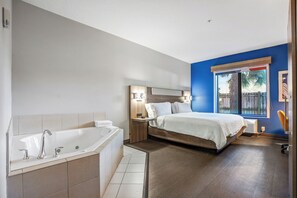Een moderne slaapkamer met een groot bed, een vastgezet hoofdbord en een raam met uitzicht op palmbomen.