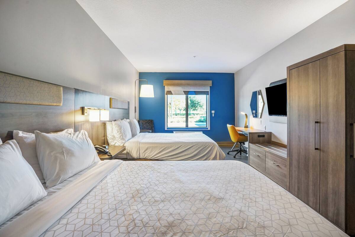Een hotelkamer met twee bedden, een bureau, een stoel, een kledingkast en een televisie.